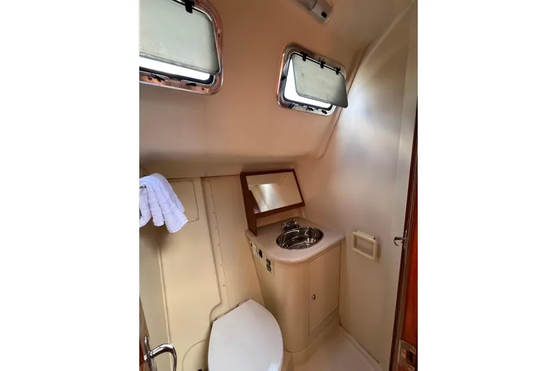 Slide: The Image of Compact bathroom in 2005 Hunter 44 Deck Salon yacht with sink, toilet, and porthole windows. - 46