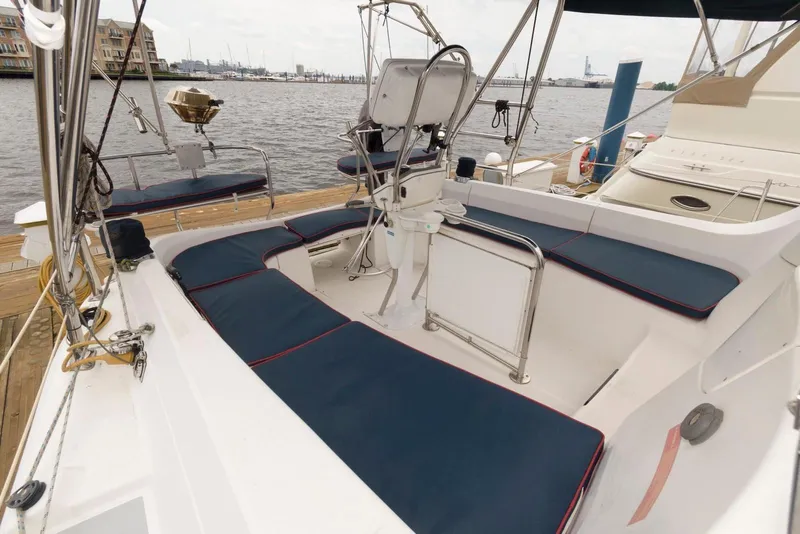 Slide: The Image of 2005 Hunter 44 Deck Salon sailboat cockpit with blue cushions, docked by the waterfront. - 6