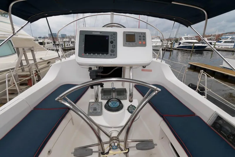 Slide: The Image of 2005 Hunter 44 Deck Salon cockpit with navigation equipment, steering wheel, and marina view. - 7
