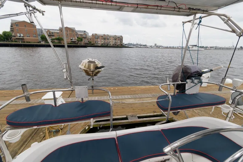 Slide: The Image of Hunter 44 Deck Salon 2005 sailboat docked, featuring cushioned seating and a waterfront view. - 9