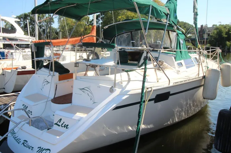 Slide: The Image of 1991 Hunter 37.5 sailboat docked, featuring green canopy and sleek design. - 2