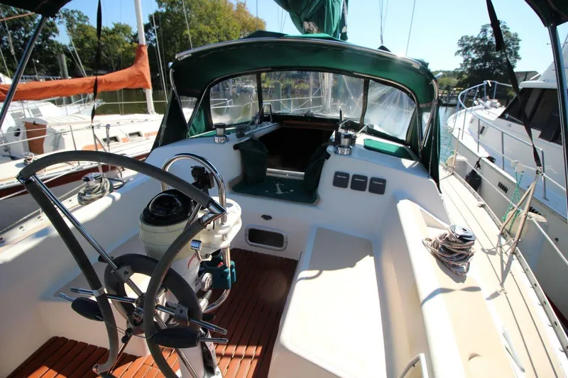 Slide: The Image of 1991 Hunter 37.5 sailboat cockpit with steering wheel and seating, docked at marina. - 5