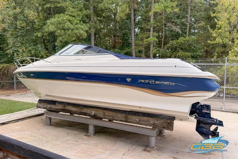 Slide: The Image of 1998 Monterey 236 Montura boat on stand, blue and white design, outdoor setting. - 21