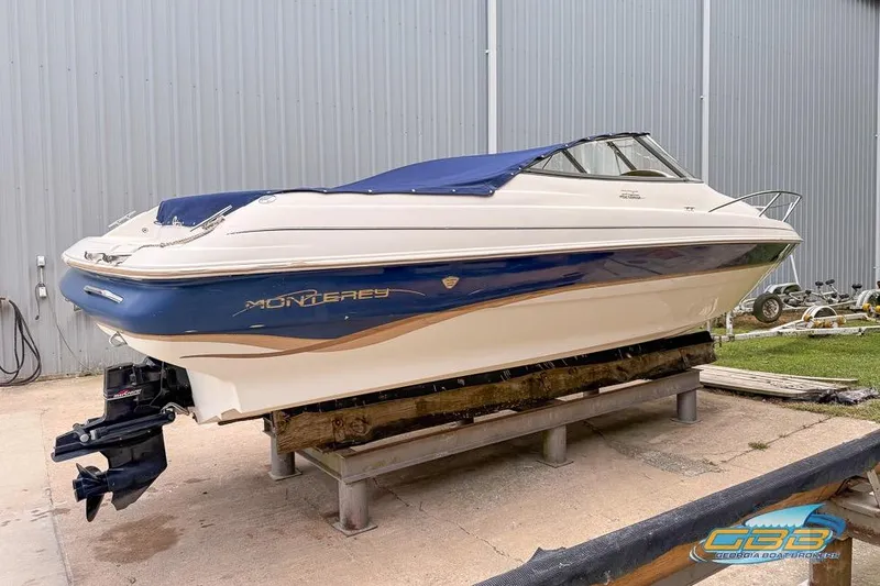 Slide: The Image of 1998 Monterey 236 Montura boat with blue cover, displayed on a wooden stand. - 23