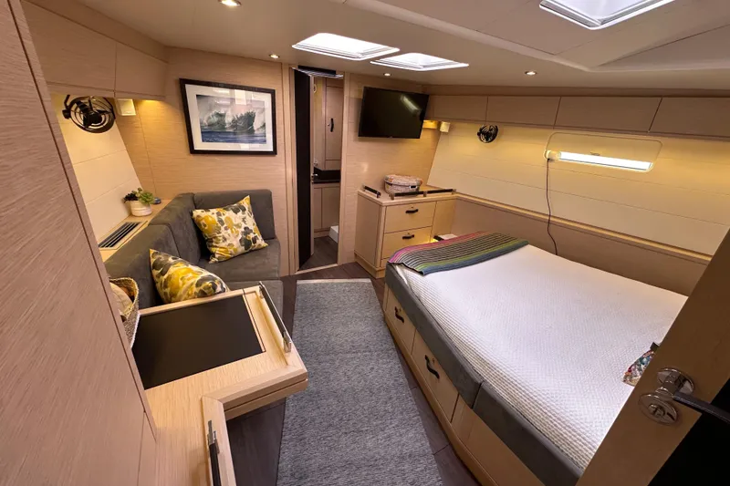 Slide: The Image of Luxurious 2017 Jeanneau 64 yacht cabin with cozy bed, sofa, and modern decor. - 116