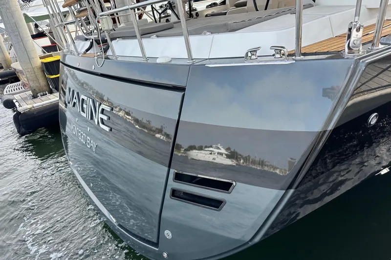 Slide: The Image of Sleek Jeanneau 64 yacht, 2017 model, docked with reflective hull and "Imagine" name. - 13
