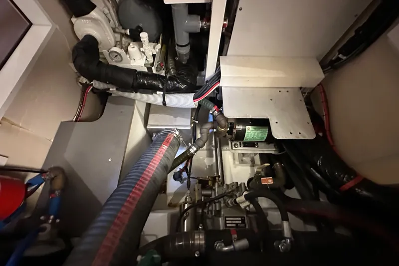 Slide: The Image of Engine room of a 2017 Jeanneau 64 yacht, showcasing mechanical components and piping. - 135