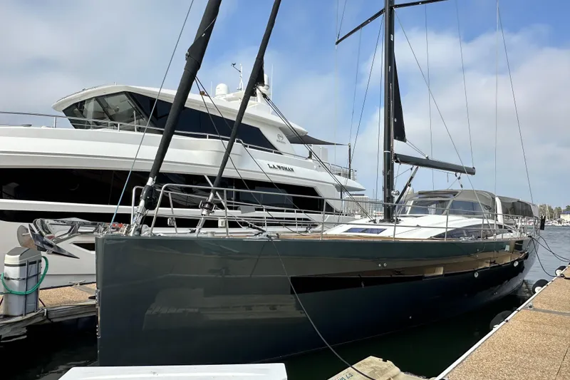 Slide: The Image of 2017 Jeanneau 64 yacht docked at marina, sleek design, black hull, and modern features. - 3