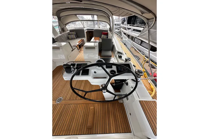 Slide: The Image of 2017 Jeanneau 64 yacht cockpit with steering wheel, teak flooring, and seating area. - 49