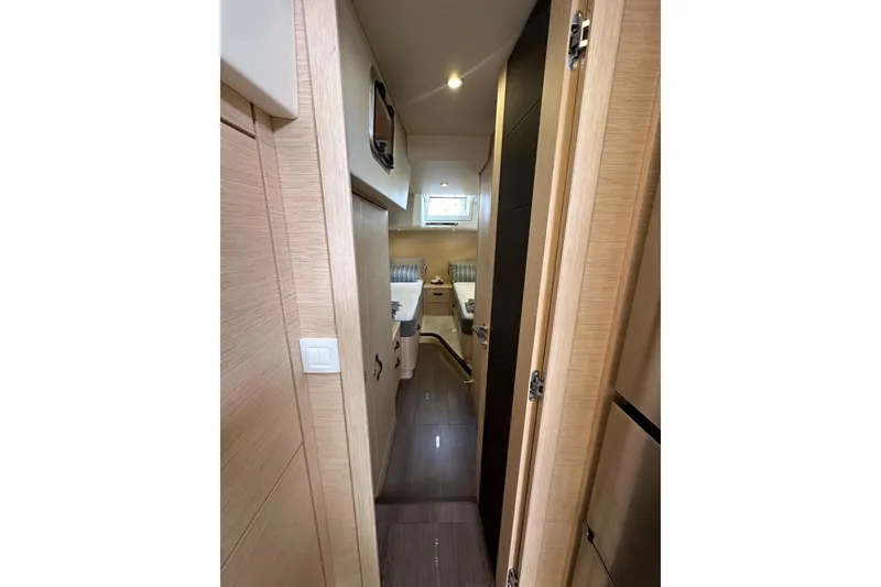 Slide: The Image of Interior hallway of 2017 Jeanneau 64 yacht, featuring modern wood finishes and compact design. - 96