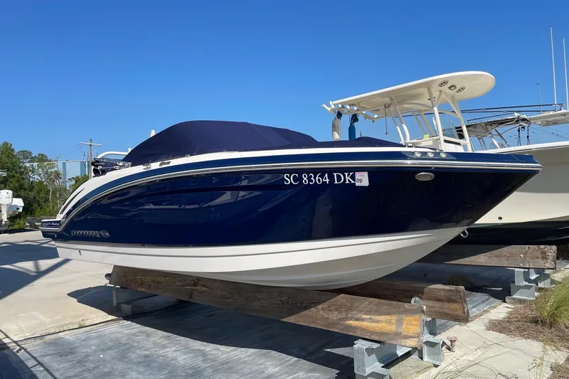 The Image of 2019 Chaparral 210 Suncoast boat with blue hull on display outdoors. - 0