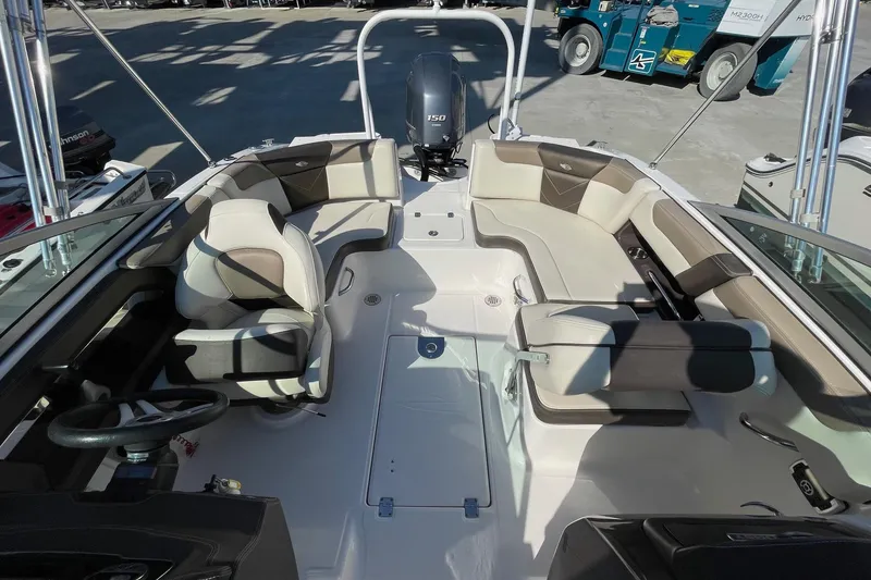 Slide: The Image of 2019 Chaparral 210 Suncoast boat interior with seating and steering wheel, docked outdoors. - 13