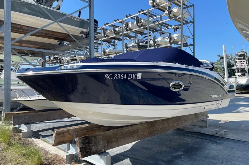 Slide: The Image of 2019 Chaparral 210 Suncoast boat in storage, blue hull, docked on a rack. - 2