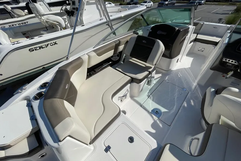 Slide: The Image of 2019 Chaparral 210 Suncoast boat interior with seating and console, docked beside other boats. - 21