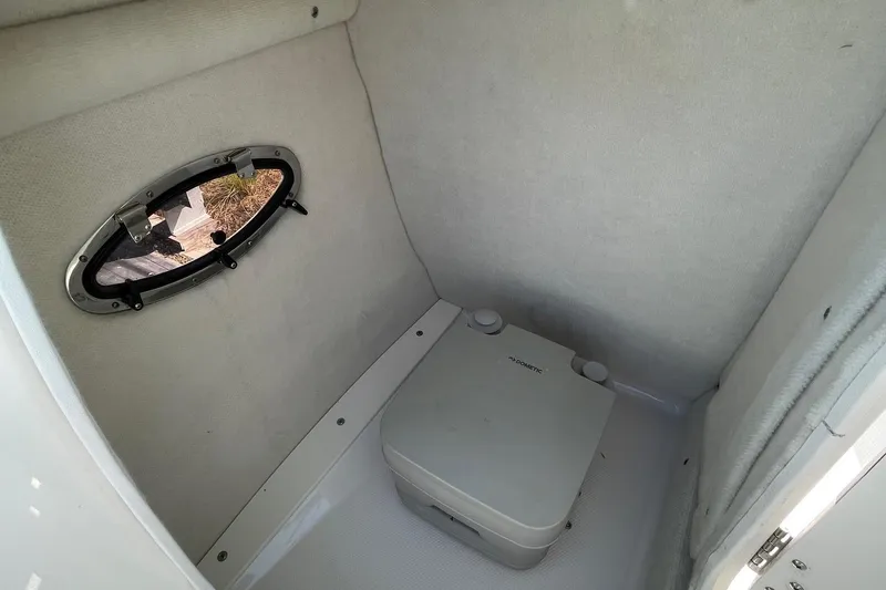 Slide: The Image of 2019 Chaparral 210 Suncoast boat interior with portable toilet and small window. - 25