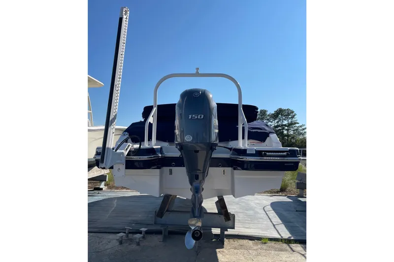 Slide: The Image of 2019 Chaparral 210 Suncoast boat with outboard motor, docked under clear blue sky. - 45