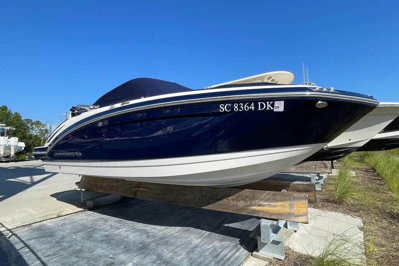 Slide: The Image of 2019 Chaparral 210 Suncoast boat on display, blue hull, parked outdoors. - 6
