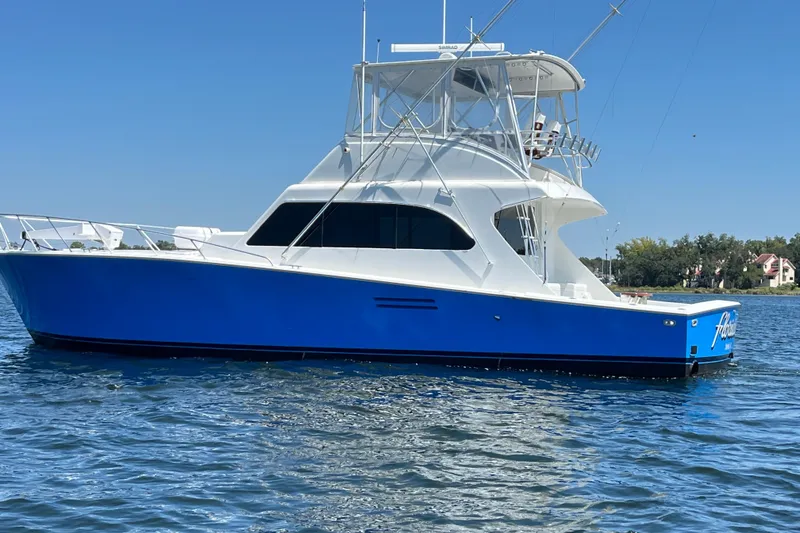 Slide: The Image of 1997 Post Sportfish boat with blue hull on calm water, clear sky background. - 1