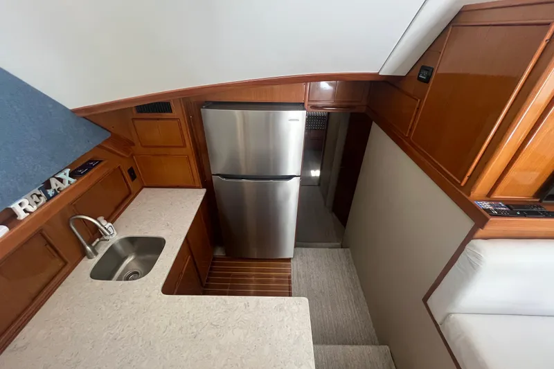 Slide: The Image of 1997 Post Sportfish yacht interior with kitchenette, stainless steel fridge, and wooden cabinetry. - 22