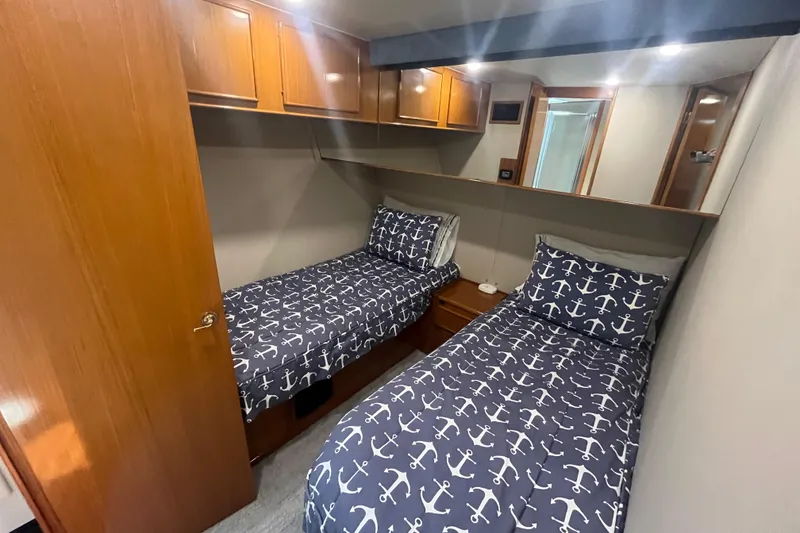 Slide: The Image of Cozy cabin with twin beds and anchor-themed bedding on a 1997 Post Sportfish boat. - 29