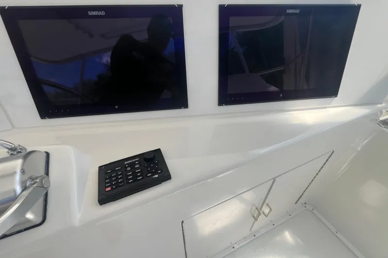 Slide: The Image of 1997 Post Sportfish boat dashboard with dual Simrad displays and control panel. - 48