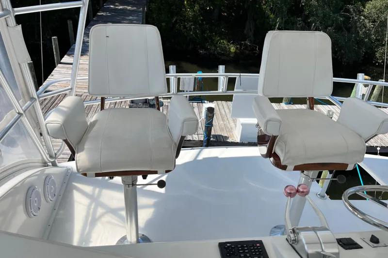 Slide: The Image of 1997 Post Sportfish boat helm with two white captain chairs and control panel. - 58