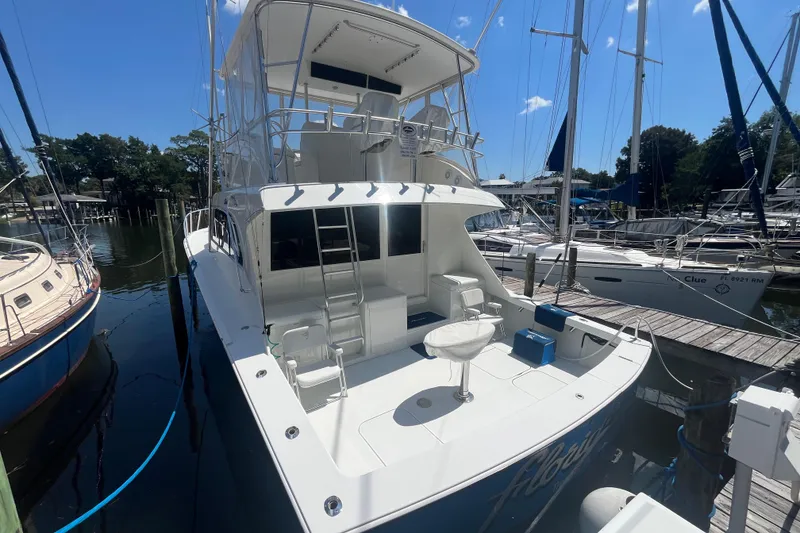 Slide: The Image of 1997 Post Sportfish boat docked at marina, featuring spacious deck and seating area. - 68