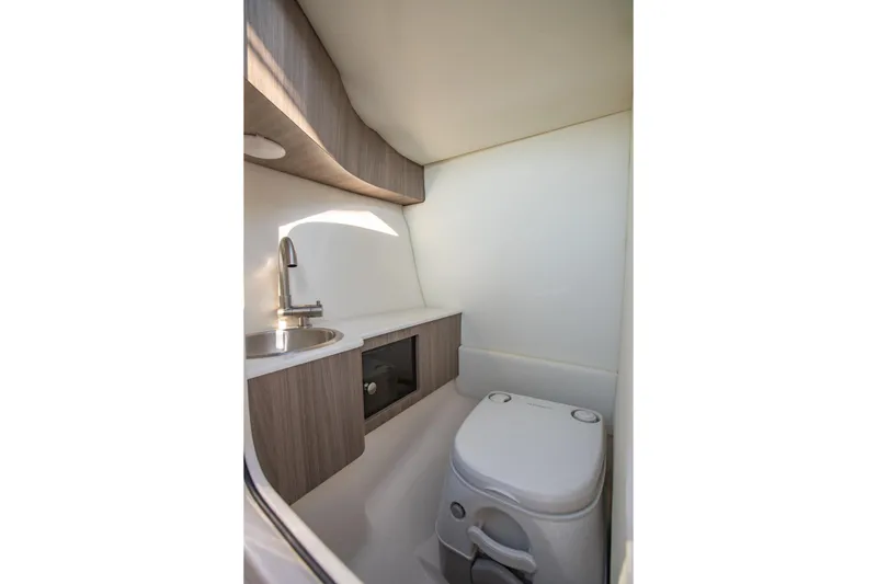 Slide: The Image of 2020 Regal LS6 boat bathroom with sink, toilet, and wooden cabinetry. - 15