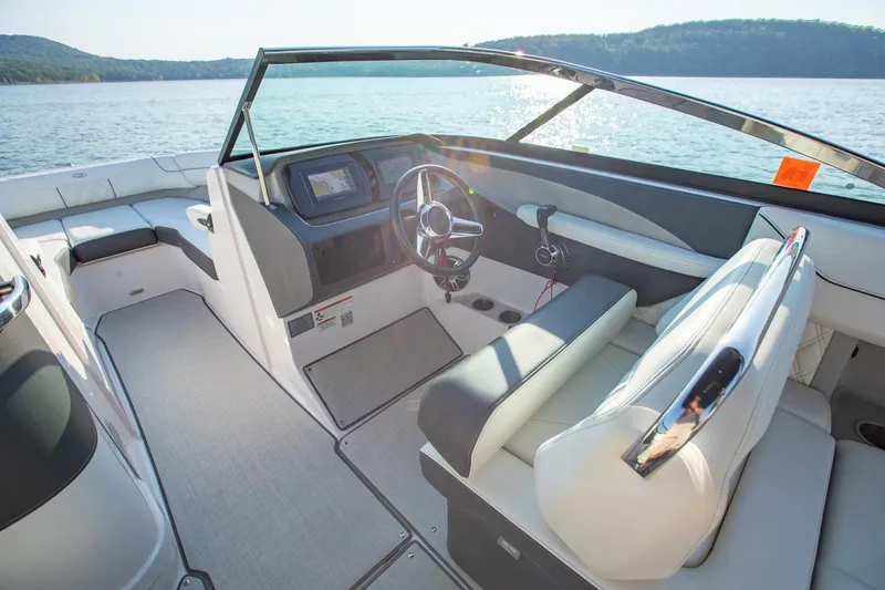 Slide: The Image of 2020 Regal LS6 boat interior with steering wheel, dashboard, and seating on a lake. - 16