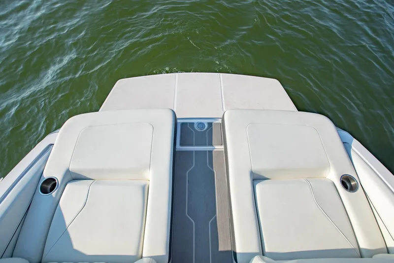 Slide: The Image of 2020 Regal LS6 boat swim platform with cushioned seating and cup holders on water. - 8