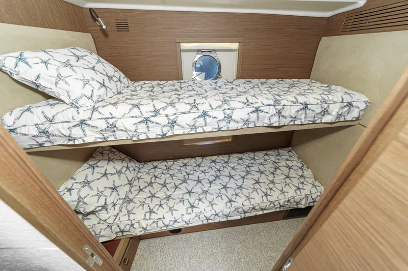 Slide: The Image of 2017 Monte Carlo MC5S yacht cabin with starfish-patterned bunk beds and porthole window. - 57