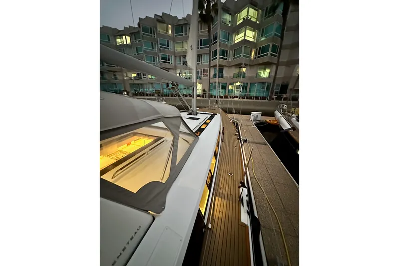 Slide: The Image of Beneteau Oceanis 55.1 yacht docked near modern apartments, evening lighting, 2021 model. - 10