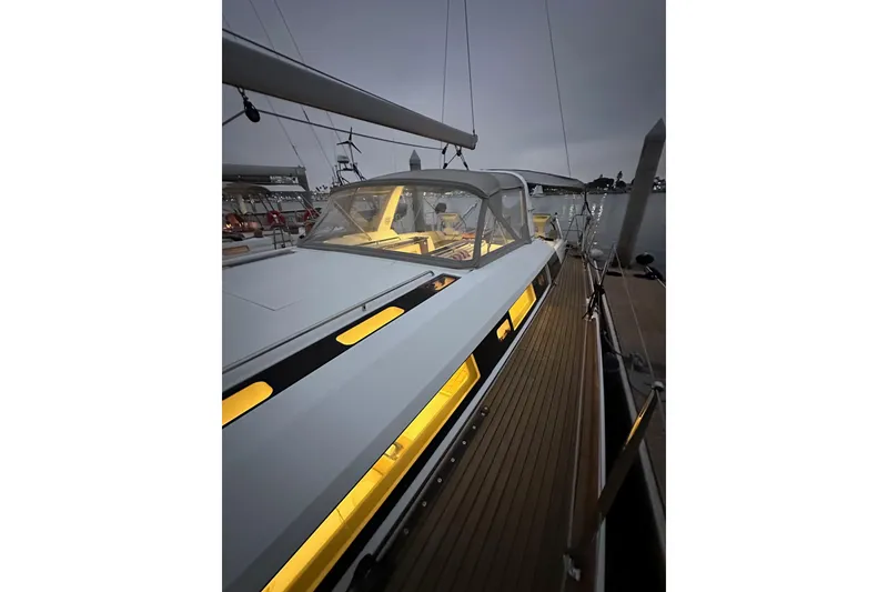 Slide: The Image of 2021 Beneteau Oceanis 55.1 yacht with illuminated deck at dusk, docked in a marina. - 19