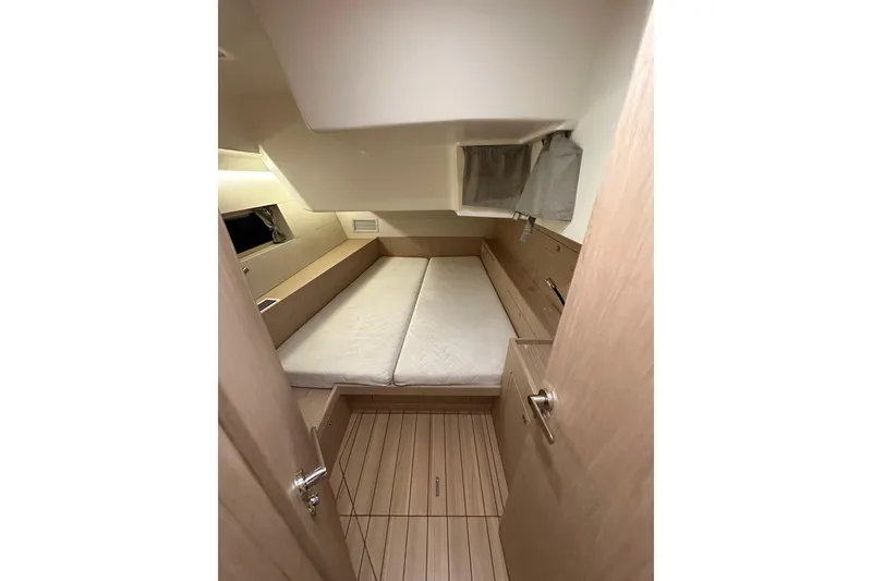 Slide: The Image of Interior cabin of 2021 Beneteau Oceanis 55.1 yacht, featuring a cozy bed and wooden flooring. - 52