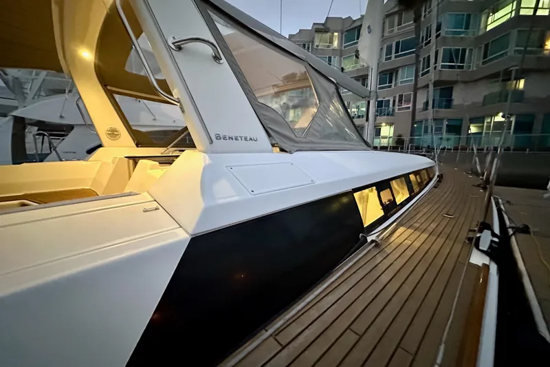 Slide: The Image of 2021 Beneteau Oceanis 55.1 yacht docked, showcasing sleek design and illuminated interior. - 9