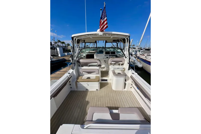 Slide: The Image of 2018 Wellcraft 290 Coastal boat interior with seating, docked at marina under clear blue sky. - 11