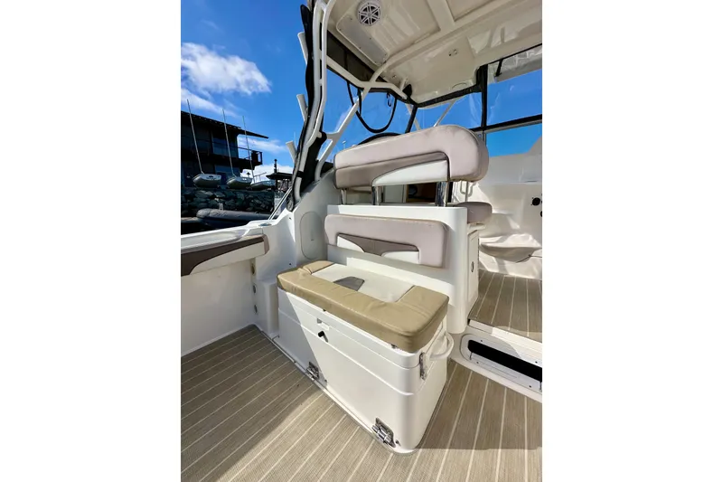 Slide: The Image of 2018 Wellcraft 290 Coastal boat interior with cushioned seating and clear blue sky. - 14