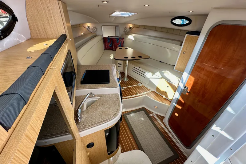 Slide: The Image of 2018 Wellcraft 290 Coastal cabin interior with kitchenette, seating, and wooden accents. - 27
