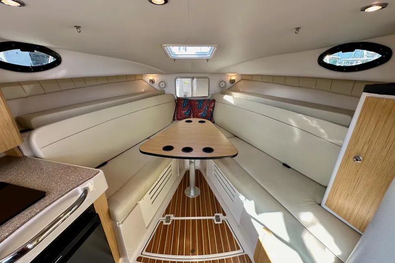 Slide: The Image of 2018 Wellcraft 290 Coastal cabin interior with seating, table, and wood accents. - 29