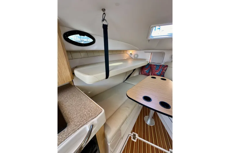 Slide: The Image of 2018 Wellcraft 290 Coastal cabin interior with seating, table, and porthole window. - 30