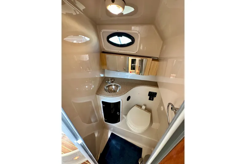 Slide: The Image of 2018 Wellcraft 290 Coastal boat bathroom with sink, toilet, and porthole window. - 36