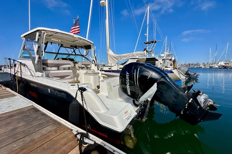 Slide: The Image of 2018 Wellcraft 290 Coastal boat docked, featuring Mercury outboard engine, clear blue sky. - 9
