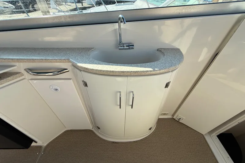 Slide: The Image of Compact sink area on a 2000 Monterey 322 Cruiser boat, featuring storage cabinets. - 13
