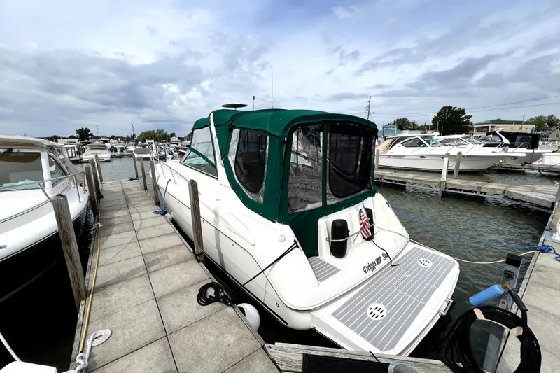 Slide: The Image of 2000 Monterey 322 Cruiser docked at marina, featuring green canopy and spacious deck. - 2