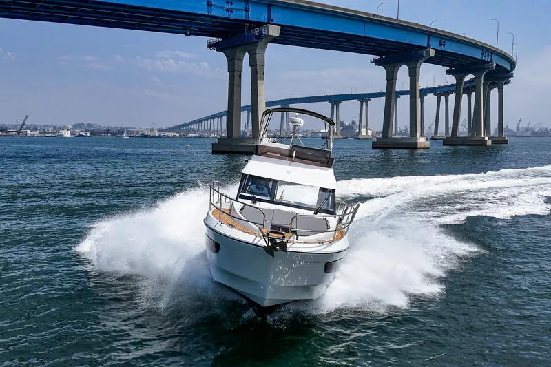 Slide: The Image of 2023 Beneteau Antares 11 Fly cruising under a large bridge on open water. - 16