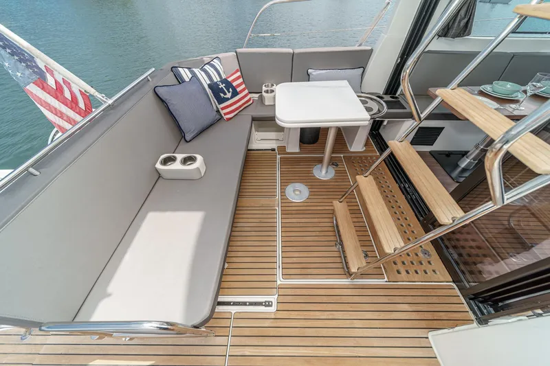 Slide: The Image of 2023 Beneteau Antares 11 Fly deck with seating, table, and American flag. - 34
