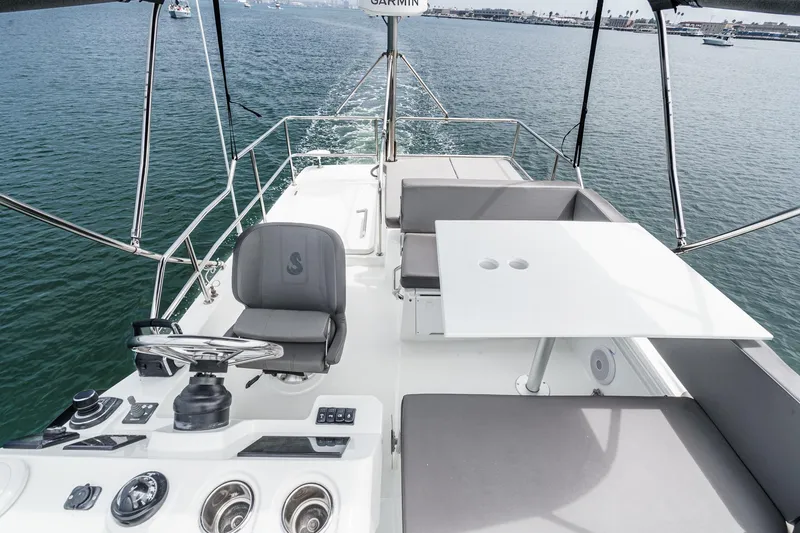 Slide: The Image of 2023 Beneteau Antares 11 Flybridge with helm, seating, and table on open water. - 55