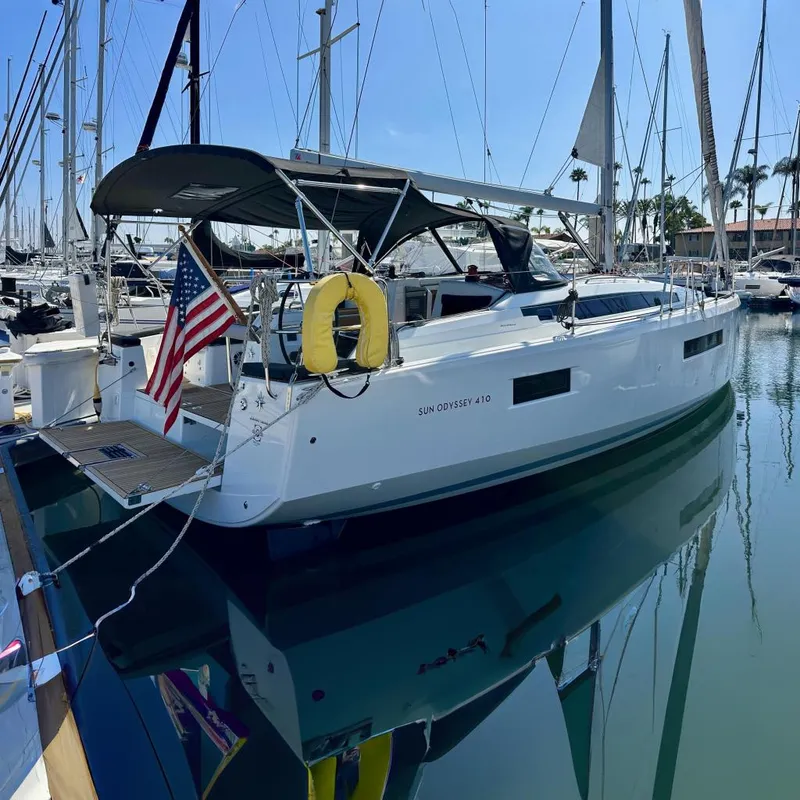 Slide: The Image of 2022 Jeanneau Sun Odyssey 410 sailboat docked in marina with American flag. - 0