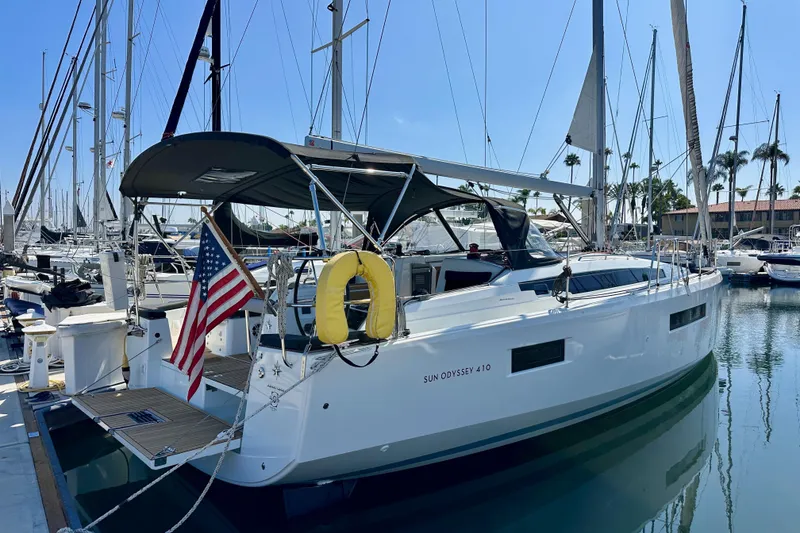 Slide: The Image of 2022 Jeanneau Sun Odyssey 410 sailboat docked in marina with American flag. - 1