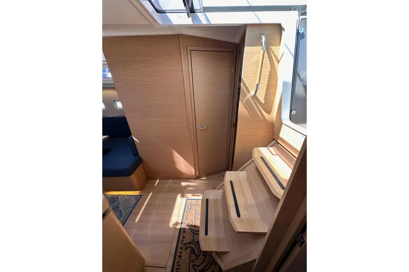 Slide: The Image of Interior of 2022 Jeanneau Sun Odyssey 410 sailboat, featuring wooden stairs and seating area. - 44